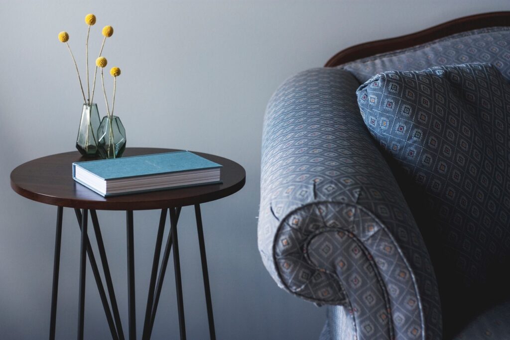 Imagen que ilustra la sección de tapicería y relax, muestra un sofá mullido junto a una acogedora mesita de noche